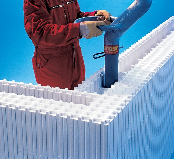 A builder guiding concrete into the Wallform insulated concrete formwork system using a swan neck nozzle