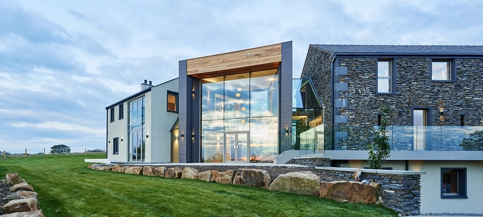 Award winning self build home built using the BecoWallform 438 system, consisting of a white rendered farmhouse wing, a glazed central entrance lobby and a barn-like wing with stone cladding