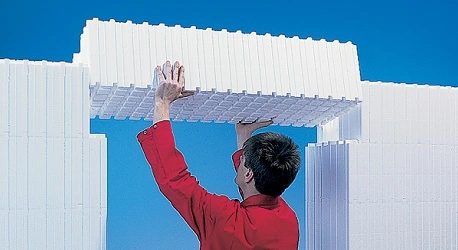 A man putting a Wallform ICF Lintel wallblock into position above a doorway