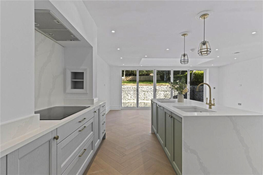 Contemporary white kitchen running into the dining space with large sliding doors to the rear